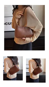 Detail view of dark brown crescent underarm bag with gold logo and smooth leather texture