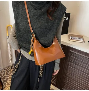 Detail van karamelbruine hobo-schoudertas met kwastje en gladde lederen afwerking