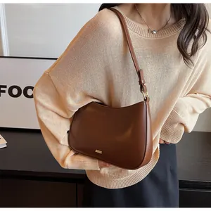 Detail of dark brown semi-circle hobo bag made of glossy PU leather with metal logo