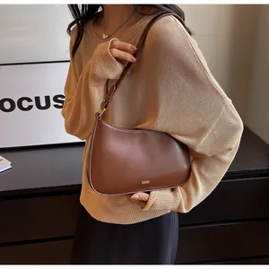 Detail of vintage brown leather underarm bag with gold logo and adjustable shoulder strap