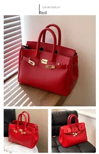 Detailansicht der roten Tote-Bag aus genarbtem Leder mit eleganten goldenen Metallschnallen