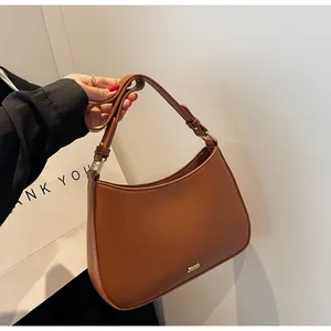Detail view of the golden JASHON logo and smooth faux leather texture on the brown hobo bag