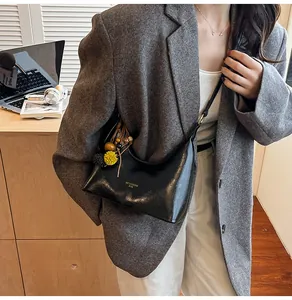 Detail van een zwarte halve maan crossbody tas met kwastje en houten kralen bedeltje