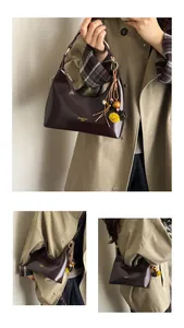 Detailweergave van de donkerbruine glanzende hobo-tas met goudkleurige details en bedels