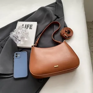 Brown matte leather half-moon shoulder bag with gold metal logo and adjustable strap