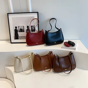 Five assorted colors of hobo bags with gold logos on a minimalist display stand