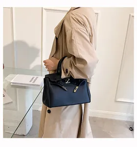 Detail einer schwarzen Einkaufstasche aus genarbtem Leder mit goldenen Elementen am Modell