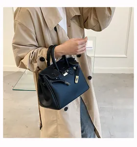 Detailansicht der schwarzen Handtasche aus Leder mit Litschimuster und goldenen Schnallen