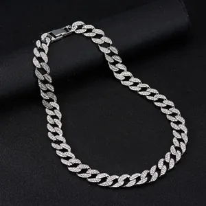 Macro detail of iced out Cuban link chain with sparkling rhinestones on a black background