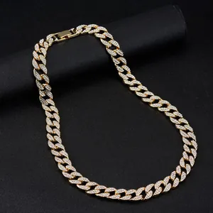Close-up of golden Cuban link necklace featuring iced-out rhinestones on black stand