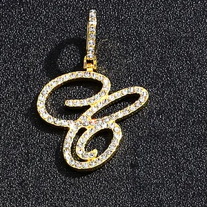 Iced out gold cursive letter pendant with pavé cubic zirconia on black display