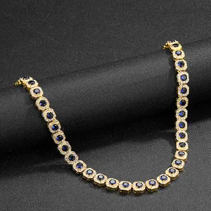 Detailed close-up of golden tennis chain with sapphire blue stones and diamond halo crystals
