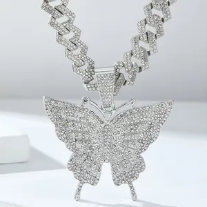 Detailopname van zilveren vlinderhanger met kristallen en een cubaanse schakelketting