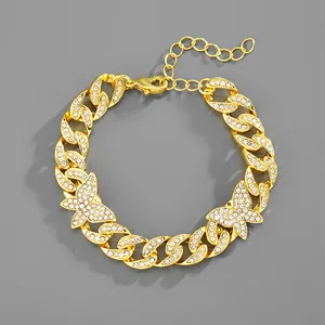 Collana a catena cubana dorata con farfalle e strass bianchi lucidi su sfondo grigio