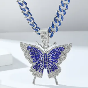 Detail van een zilveren Cubaanse ketting met vlinderhanger en blauwe en witte steentjes