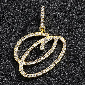 Cursive letter O gold pendant with iced out rhinestones on black leather surface