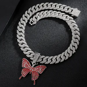 Macro detail of iced-out Cuban link chain with a sparkling red butterfly pendant