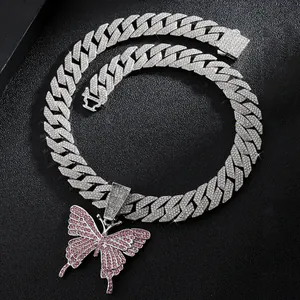 Macro view of iced out silver Cuban link chain with a pink and white butterfly pendant