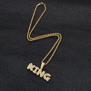 Macro shot of gold KING letter pendant with iced-out stones and twist chain