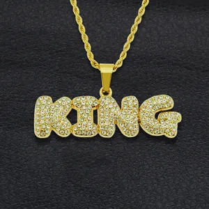 Macro shot of gold-plated KING letter pendant with iced-out white crystals on black leather