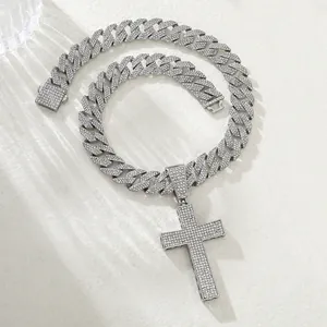 Macro shot of a silver iced-out cross pendant with a Cuban link chain on white stone texture