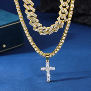 Gros plan sur une chaîne cubaine dorée et un collier tennis avec pendentif croix en cristal