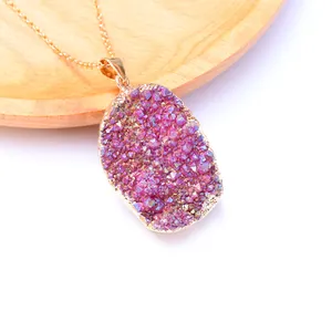 Detailopname van roze druzy kwarts ketting met gouden rand op houten dienblad