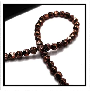 Close-up of faceted metallic bronze volcanic stone beads with shimmering texture for DIY jewelry