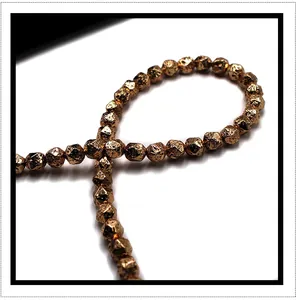 Macro detail of plated volcanic stone beads with faceted rose gold metallic texture
