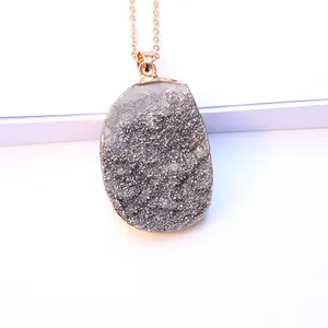 Detailopname van onregelmatige druzy hanger met vergulde randen en fijne ketting