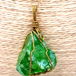 Détail d'un pendentif en cristal brut vert avec fil d'or fait main et chaîne fine