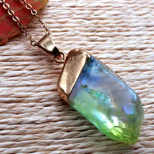 Vue détaillée du pendentif en cristal bleu irrégulier avec fil de cuivre et chaîne dorée