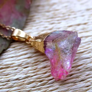 Vue macro d'un pendentif en cristal brut coloré avec fil doré et chaîne croisée