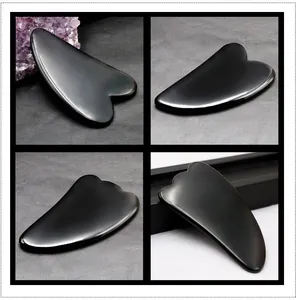 Makro-Detail von vier polierten schwarzen Obsidian Gua Sha Gesichts-Tools auf Leder