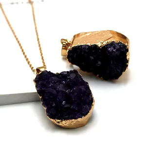 Detail van natuurlijke amethist hanger met vergulde randen aan een fijne gouden ketting
