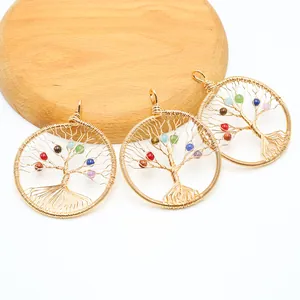 Three handmade wire-wrapped tree of life pendants with colorful crystal beads on wood