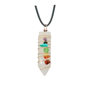 Close-up of wire wrapped crystal pendant with seven colorful chakra stones on white background