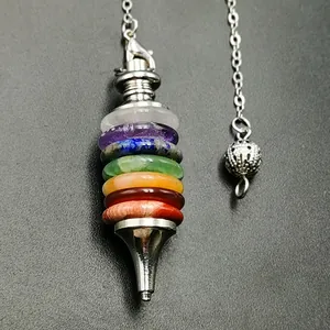 Macro detail of Seven Chakra stone pendulum pendant with silver chain on textured background