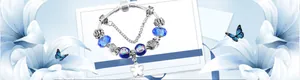 Vue détaillée du bracelet serpent en argent avec des perles en verre bleu et des breloques