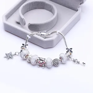 DIY Bettelarmband mit silberfarbenem Bären, rosa Schleife, Schneeflocke und Herzschlüssel