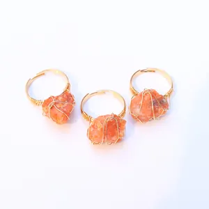 Vista macro de anillos hechos a mano con alambre dorado y piedras naturales naranjas