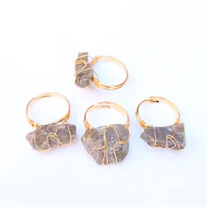 Detalle de cuatro anillos artesanales de hilo dorado con piedras naturales y banda ajustable