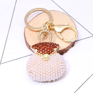 Macro shot of luxury shell pearl handbag keychain with crystal rhinestones on wood