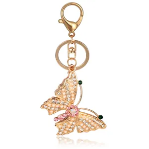 Golden butterfly keychain with sparkling crystals and pearls on white background