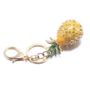 Mini yellow rhinestone pineapple keychain with golden lobster clasp on white background