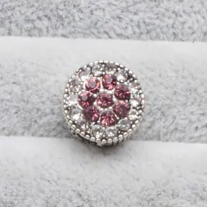Détail macro d'une perle argentée avec strass roses et blancs pour bracelets DIY