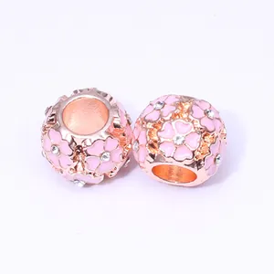 Vue macro de perles en or rose avec fleurs de cerisier en émail rose et strass