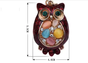 Detail of owl keychain with red enamel finish, rhinestones and colorful cat eye stones