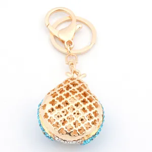Détail d'un porte-clés doré en forme de fruit avec strass bleu clair et découpe