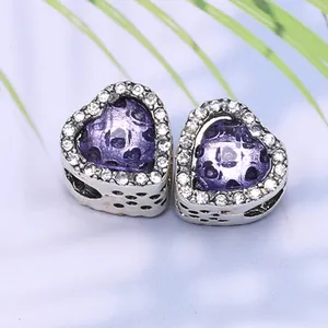 Vue macro de breloques cœur en opale violette avec pavé de cristaux et détails ajourés